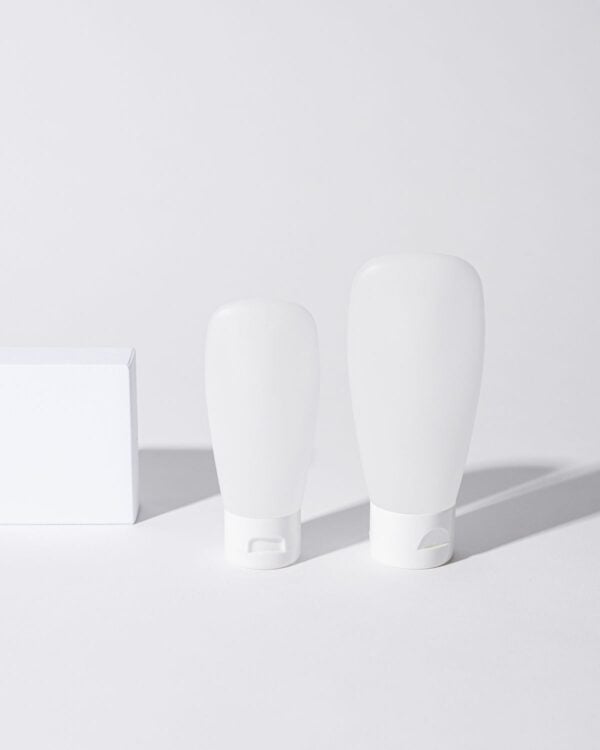 Two white cosmetic bottles on a white surface