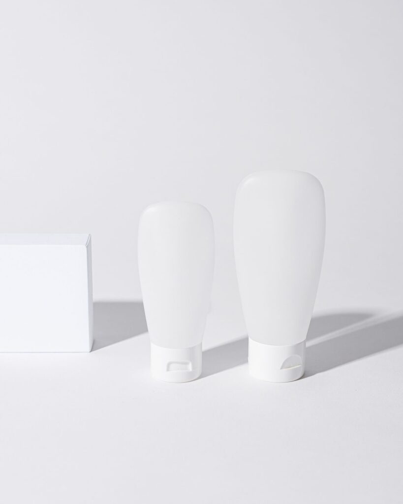 Two white cosmetic bottles on a white surface