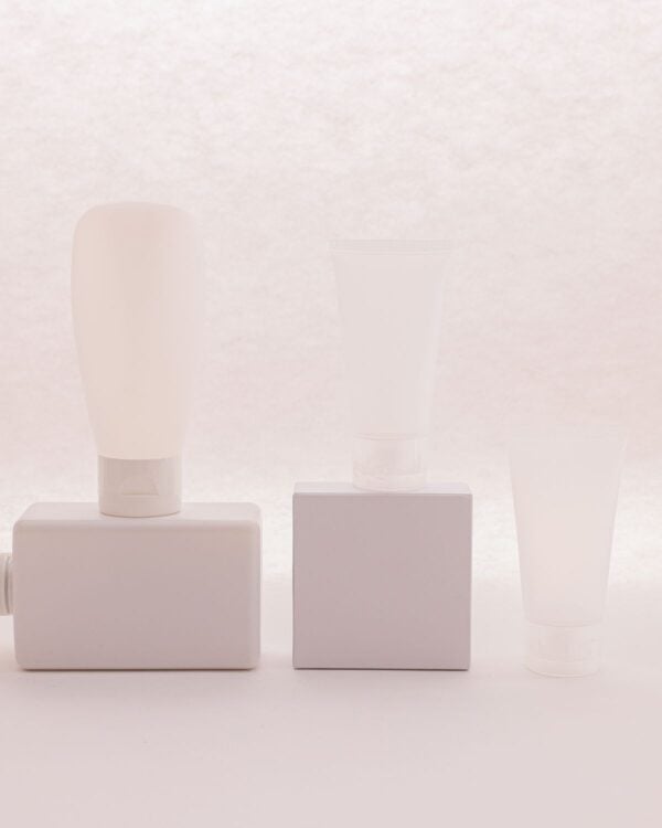 Three small white bottles arranged on pale blocks