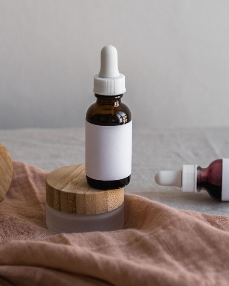 Glass jar with wooden lid and dropper bottle on linen
