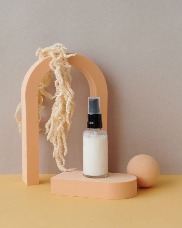 White spray bottle under a peach arch with dried grass