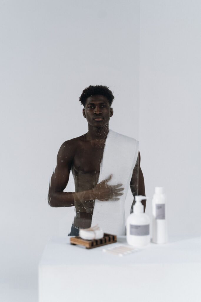 Man with a towel over his shoulder beside skincare bottles