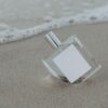 Clear perfume bottle standing on wet sand by the sea