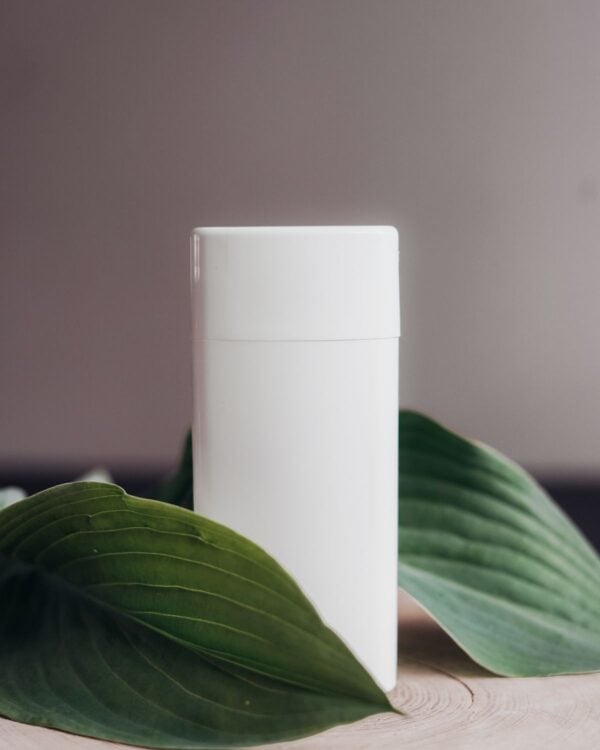 White deodorant stick beside green leaves