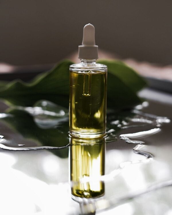 Golden oil bottle standing in water with a leaf
