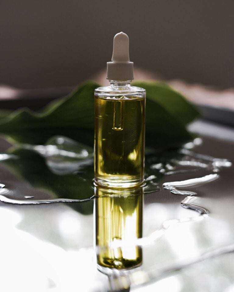 Golden oil bottle standing in water with a leaf