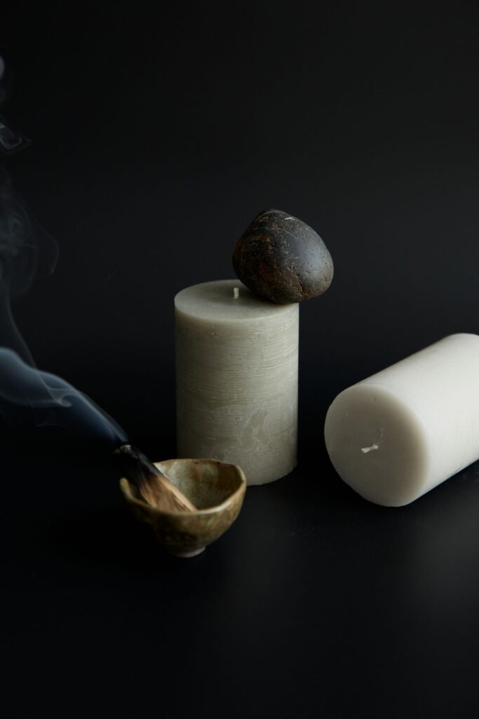 Calming still life with a stone, candle and incense bowl on black