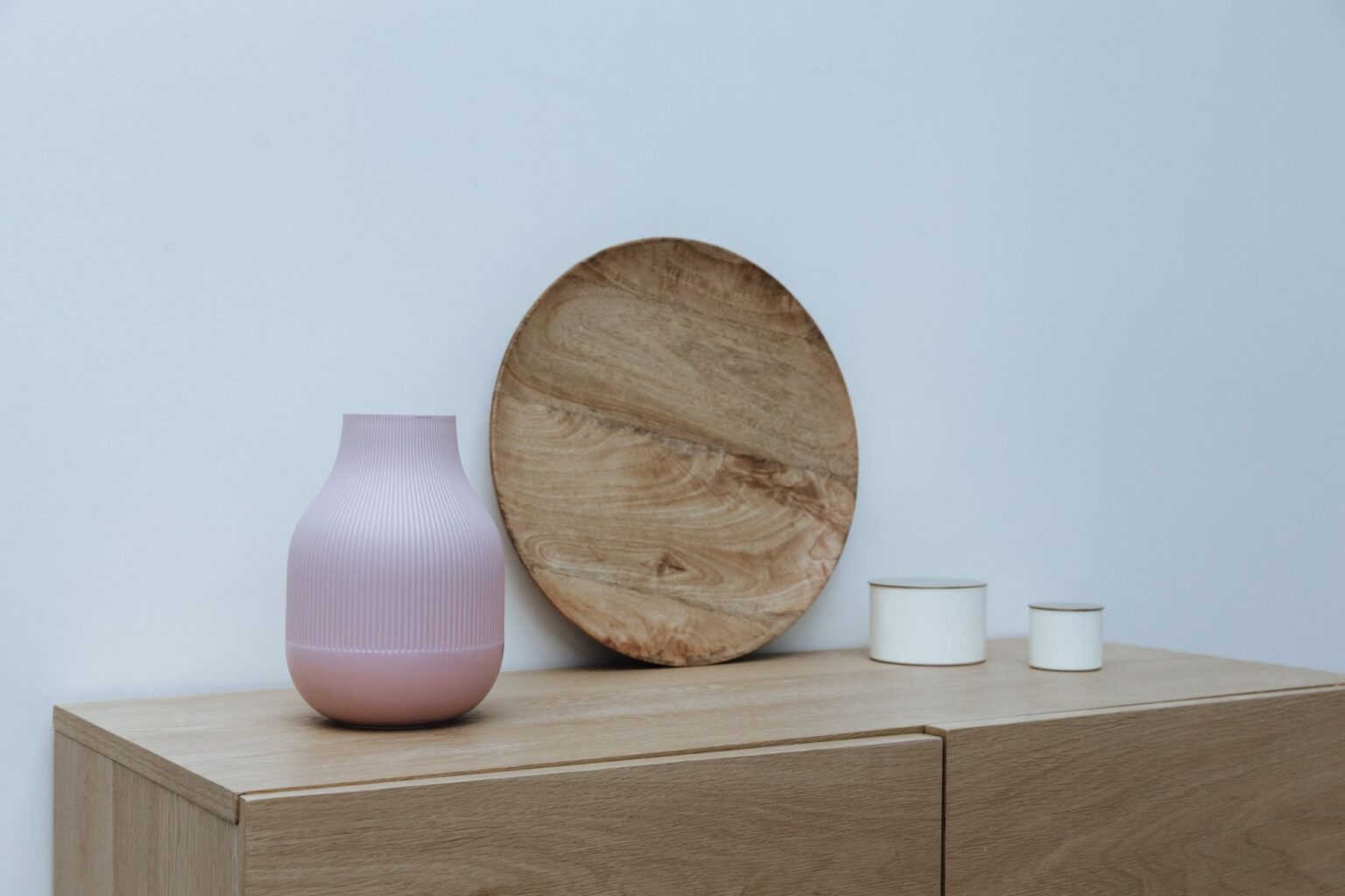 Ceramic vase and round wooden board on a sideboard