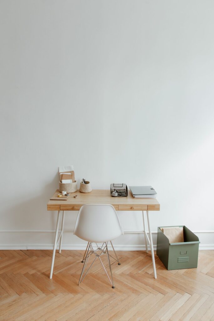 Oak writing desk with a white chair against a white wall