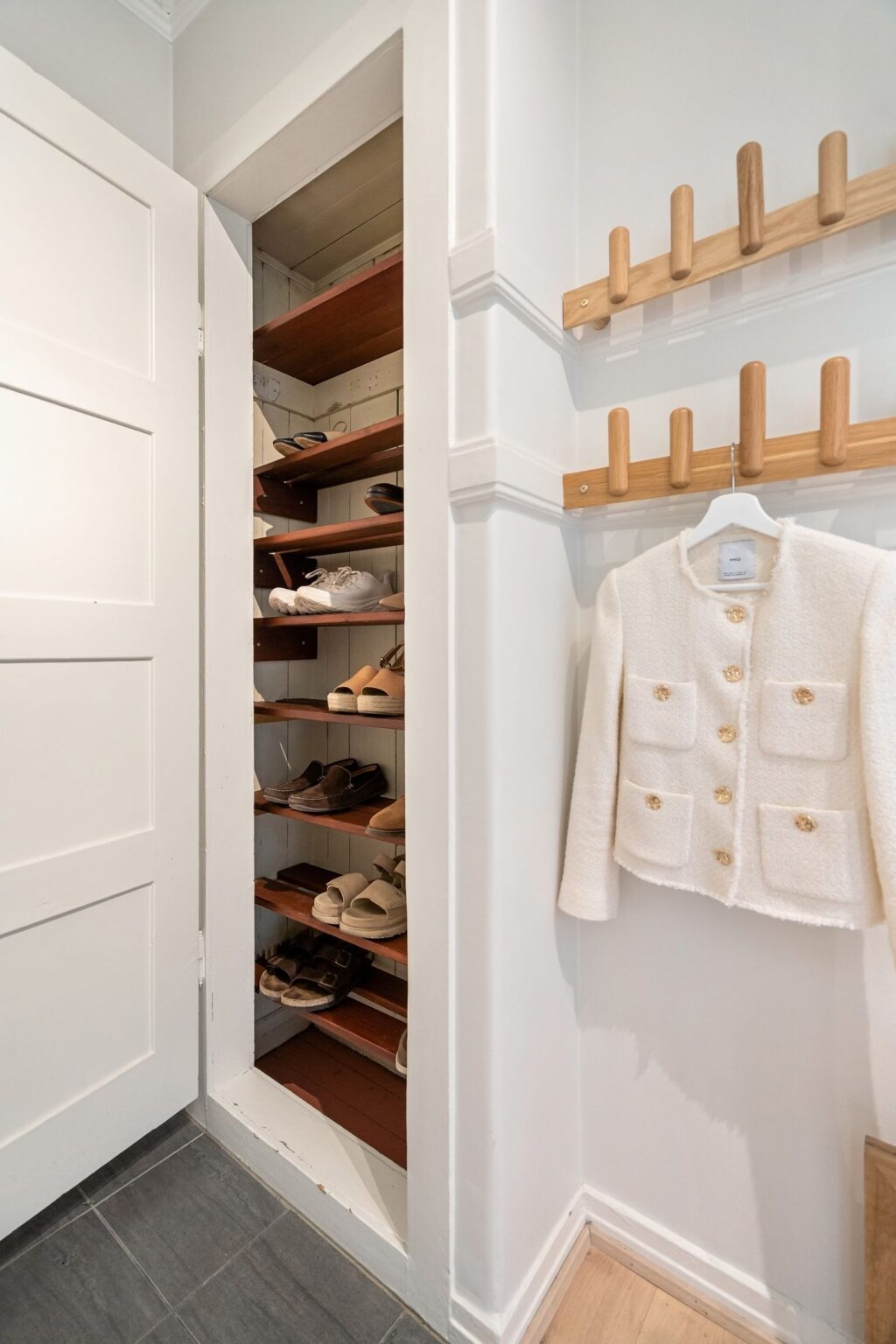 Low wooden shoe rack in a bright entryway