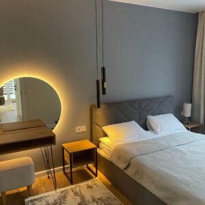 Calm bedroom with an upholstered bed and backlit round mirror