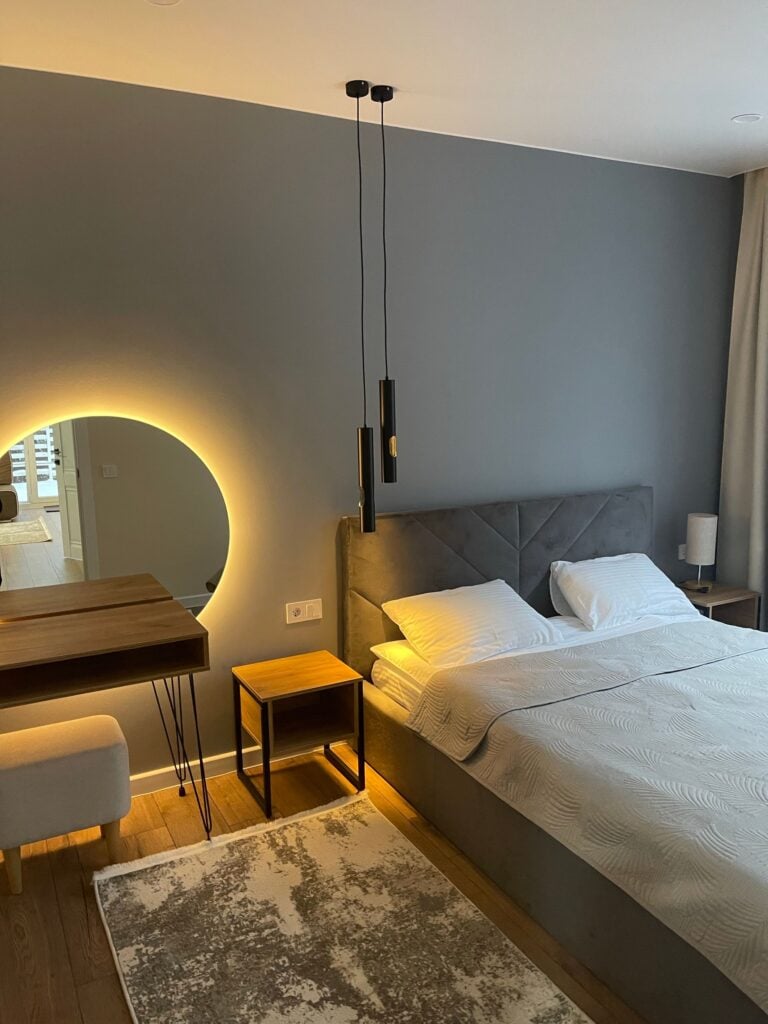 Calm bedroom with an upholstered bed and backlit round mirror