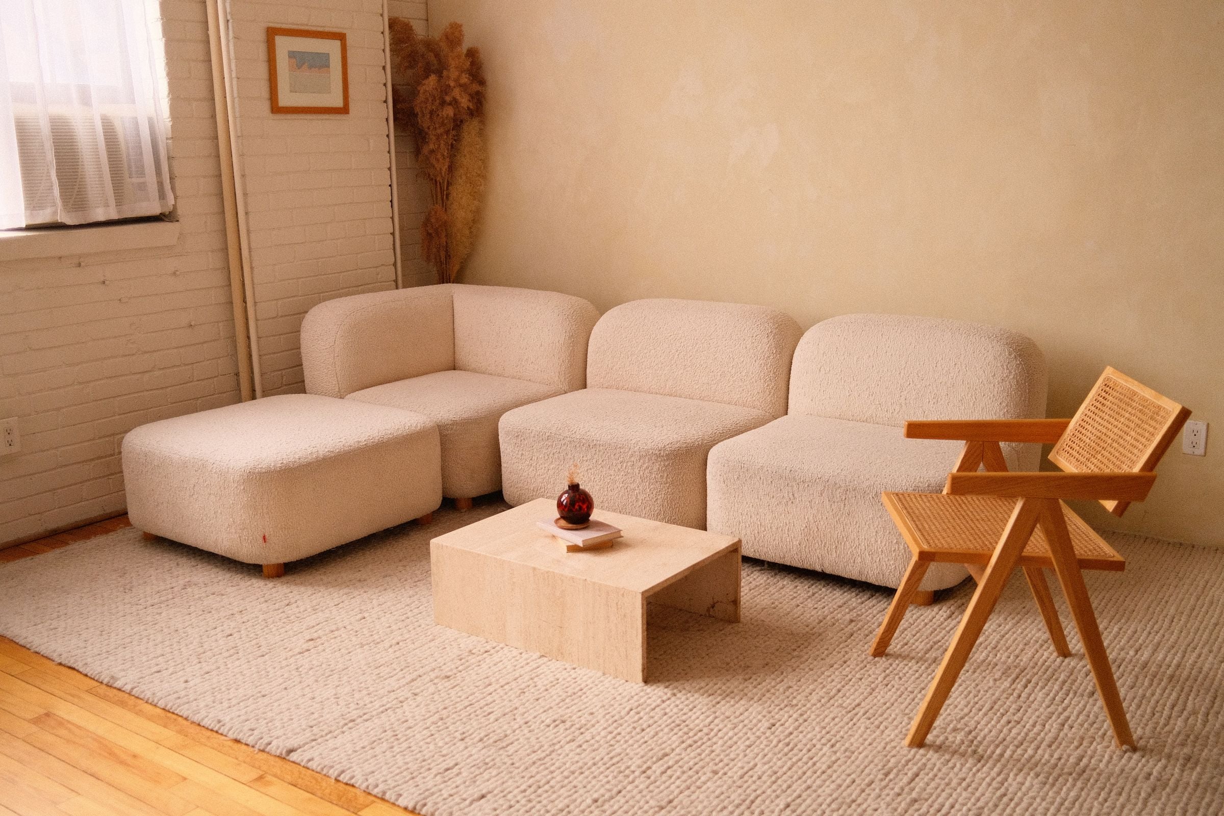 Boucle modular sofa and rattan armchair in a sunlit living room
