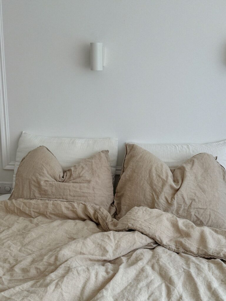 Beige linen bedding on an unmade bed