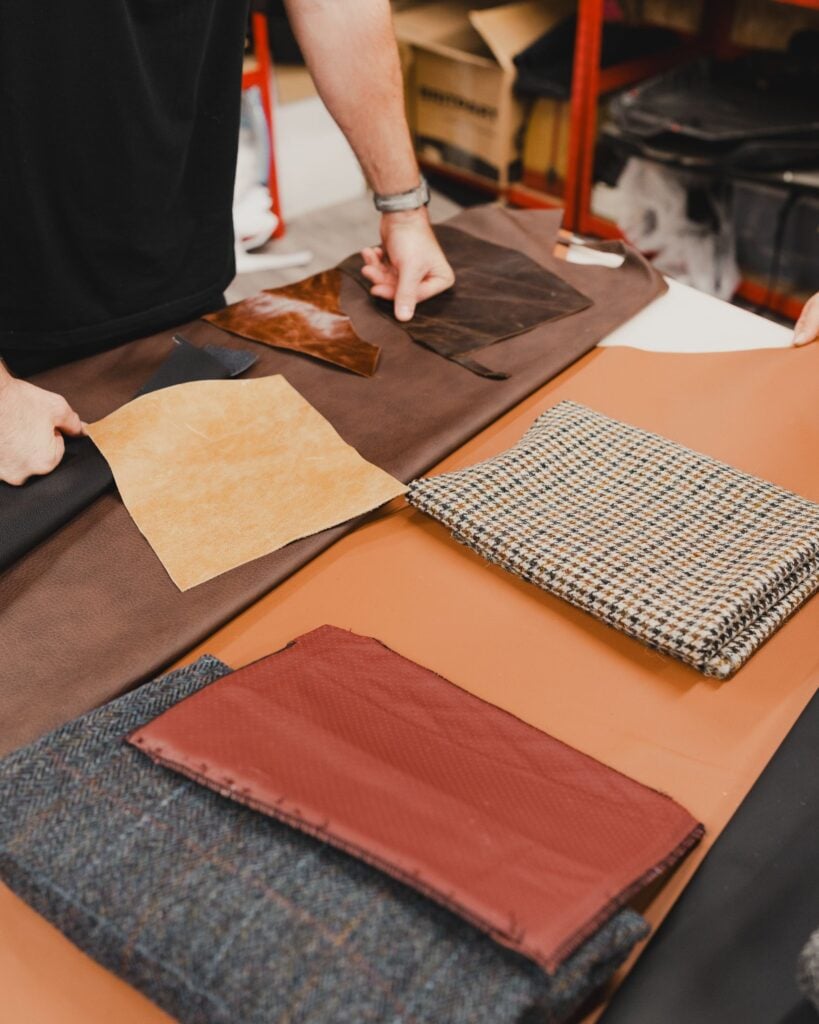 Hands arranging leather and fabric swatches in earthy tones