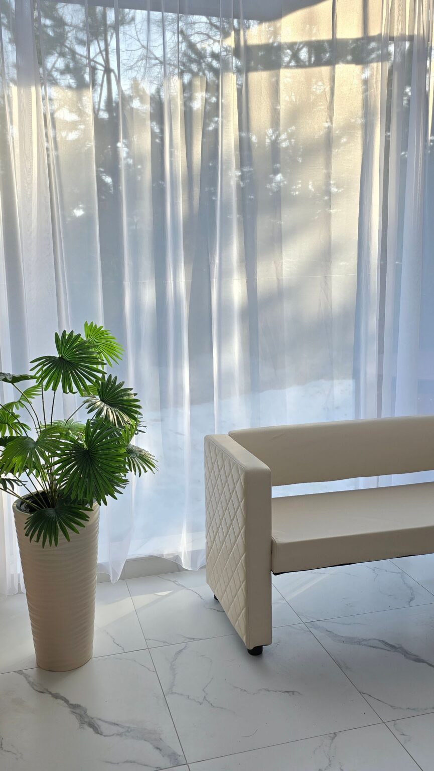 Modular sofa arm in oat upholstery beside a palm
