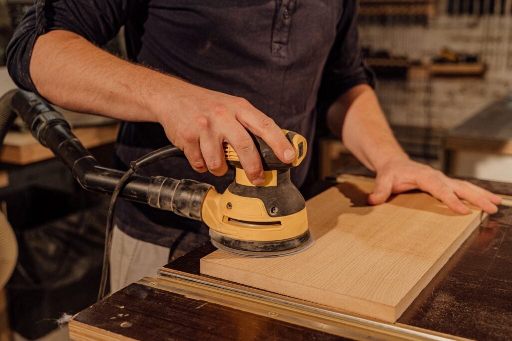 Hands sanding a wooden board in a workshop