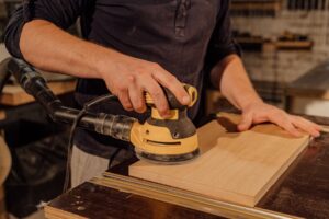 Hands sanding a wooden board in a workshop