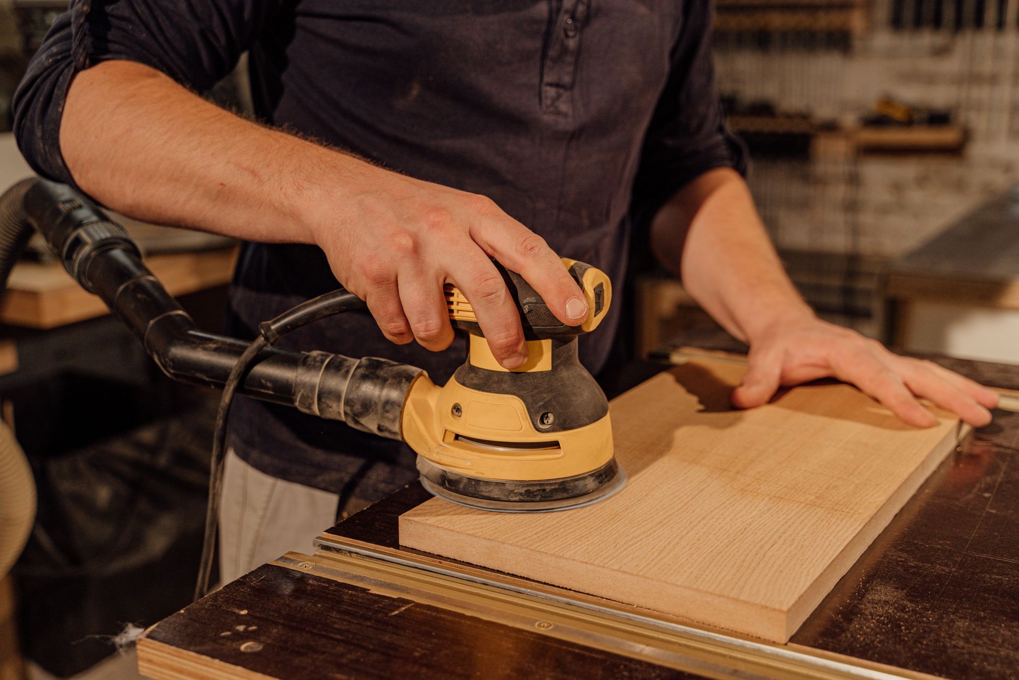 Hands sanding a wooden board in a workshop
