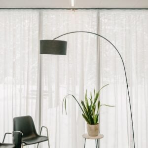Arc floor lamp beside sheer curtains