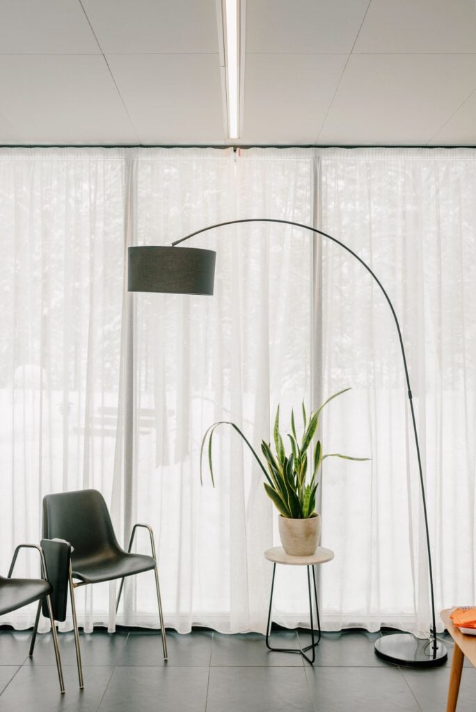 Arc floor lamp beside sheer curtains