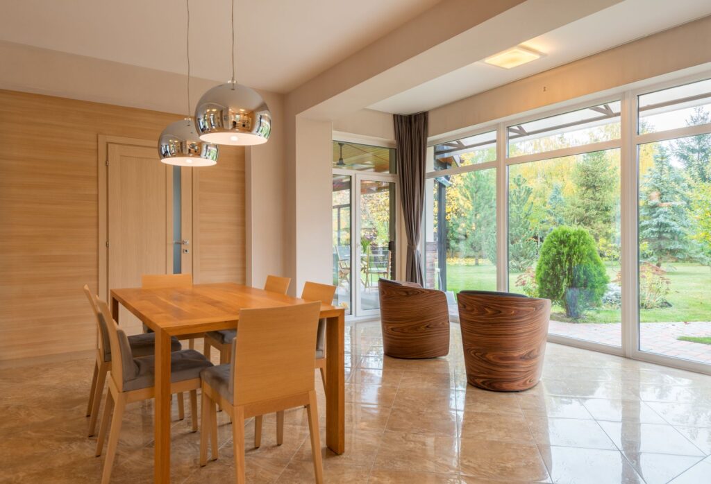Wooden dining table and chairs by tall windows