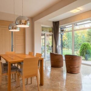Wooden dining table and chairs by tall windows