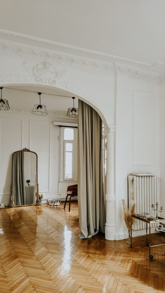 White room with an arch, linen curtains and a tall mirror