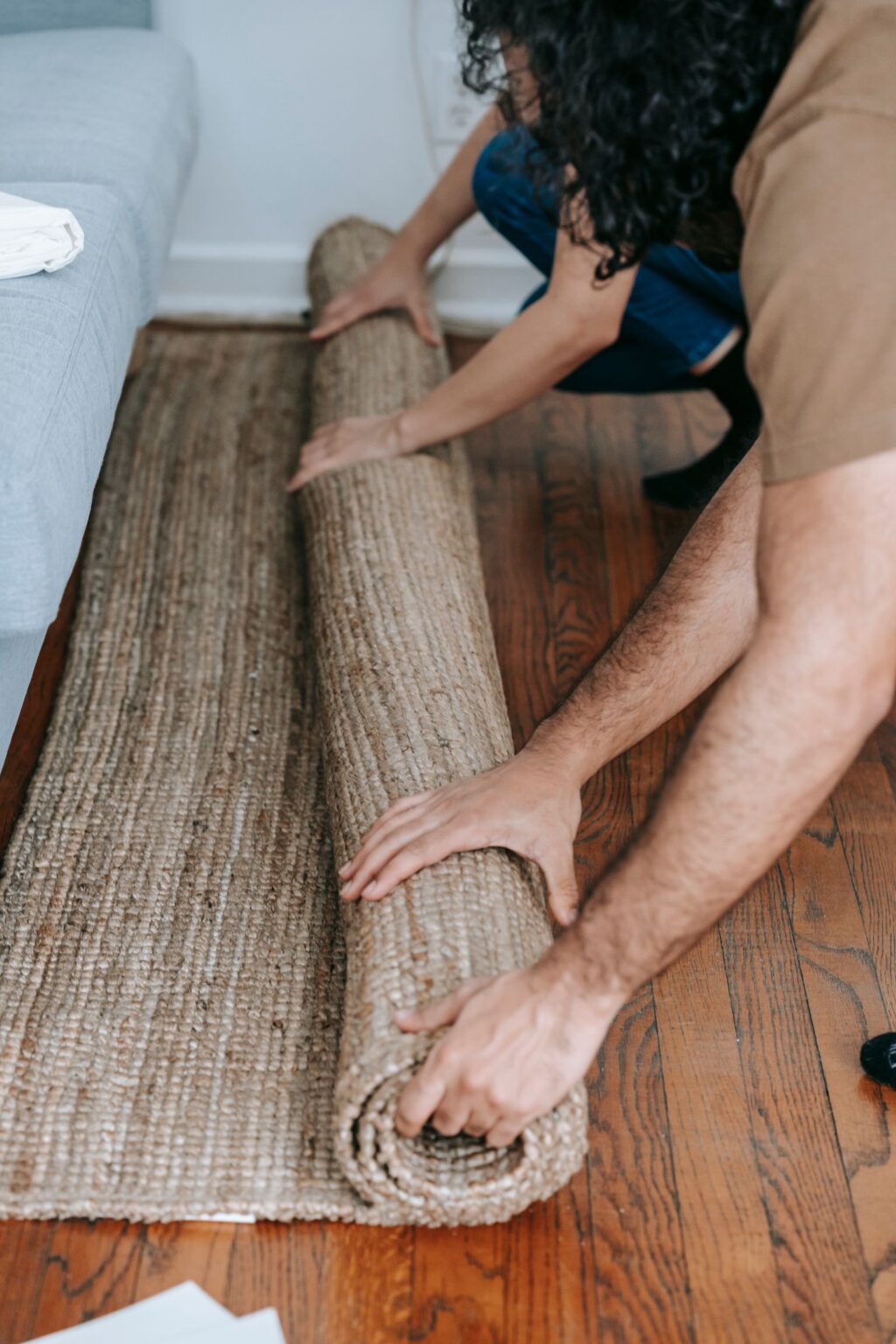 Hands unrolling a jute rug