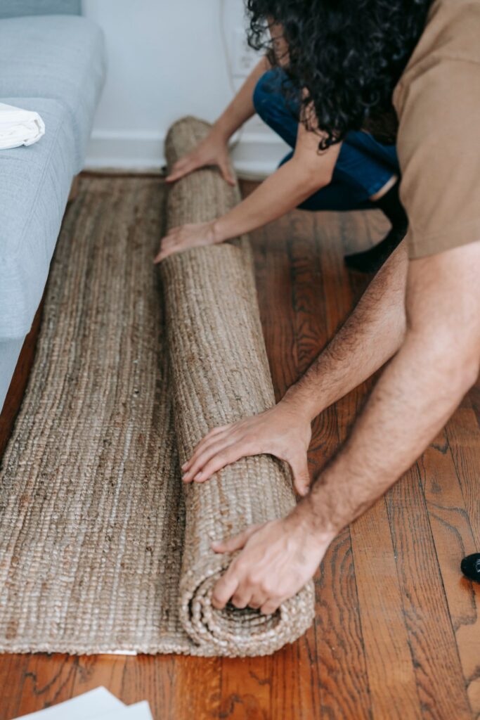 Hands unrolling a jute rug