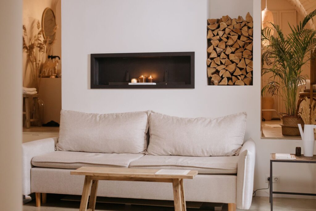 Cream sofa in front of a modern fireplace with stacked firewood