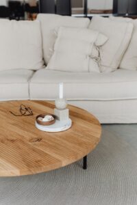 Round oak coffee table in front of a linen sofa