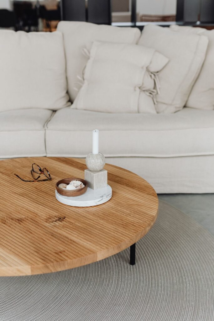 Round oak coffee table in front of a linen sofa