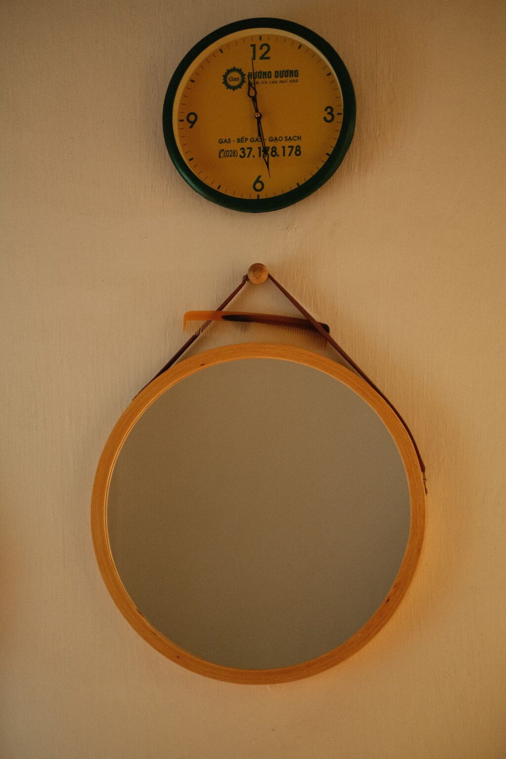 Round mirror with leather strap on a beige wall