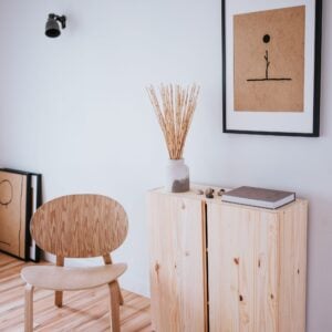 Pine storage cabinet, wooden chair and framed art in a bright room