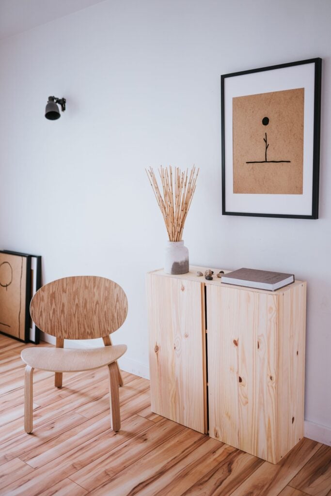 Pine storage cabinet, wooden chair and framed art in a bright room