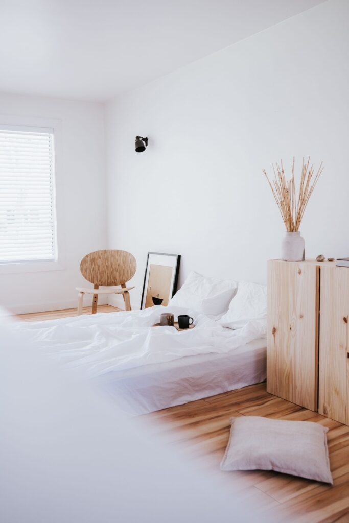 Bright bedroom with white bedding and rattan chair