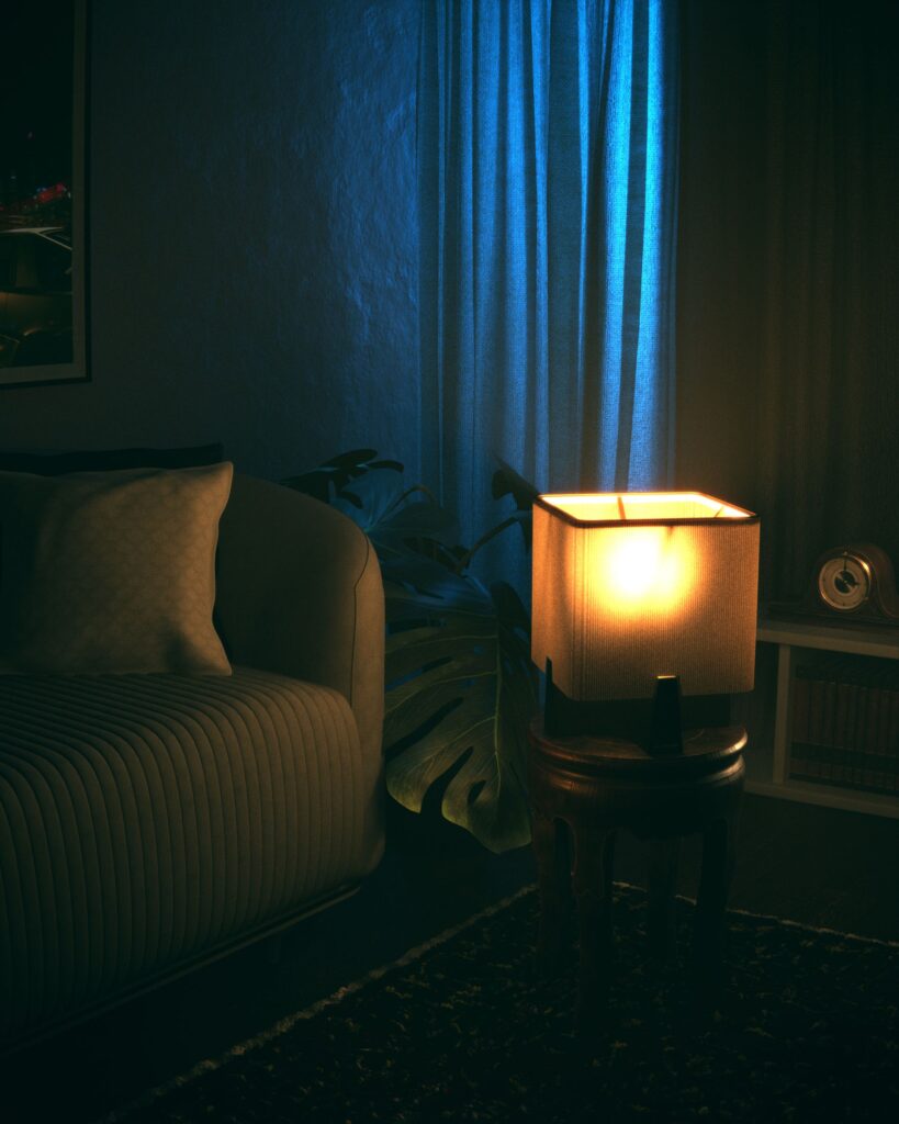 A glowing table lamp beside an armchair in a dark blue room