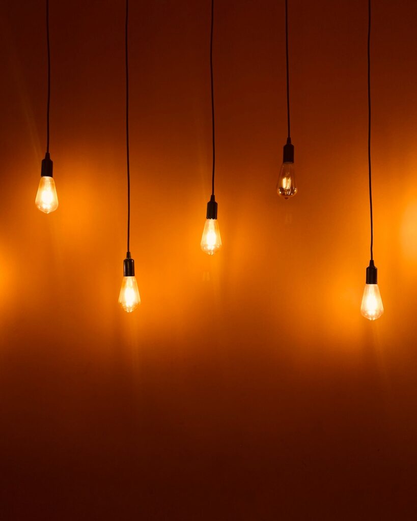 Rows of bulbs hanging on cords against an orange wall