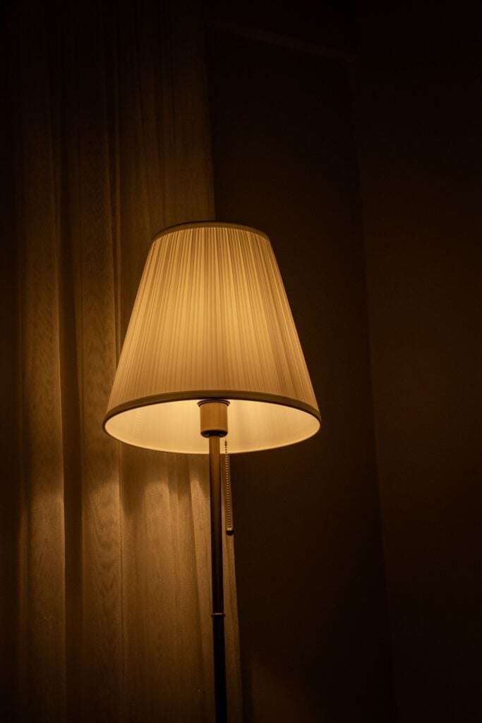 A pleated floor lamp glowing in a dark room