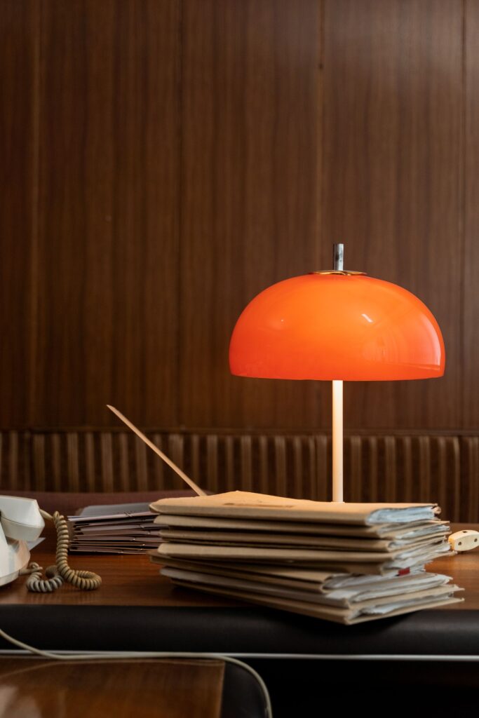 Ember Desk Lamp with an orange glass dome on a desk