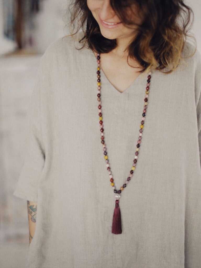 A loose undyed linen tunic dress worn with a long beaded necklace