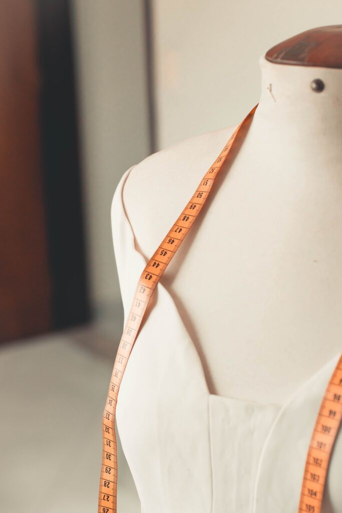 A cream dress form draped with a tape measure